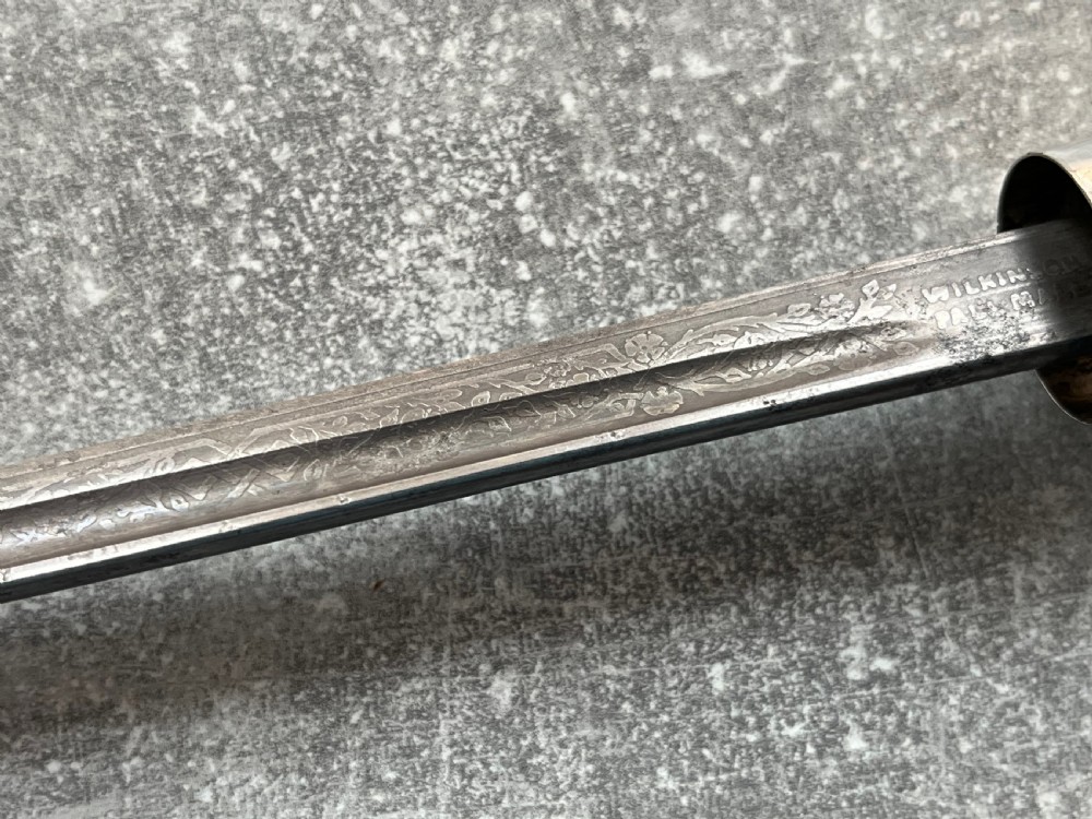 An antique chestnut wood sword stick shown unsheathed beside its shaft, featuring a root ball knob handle, silver collar mount, and long steel blade. View V
