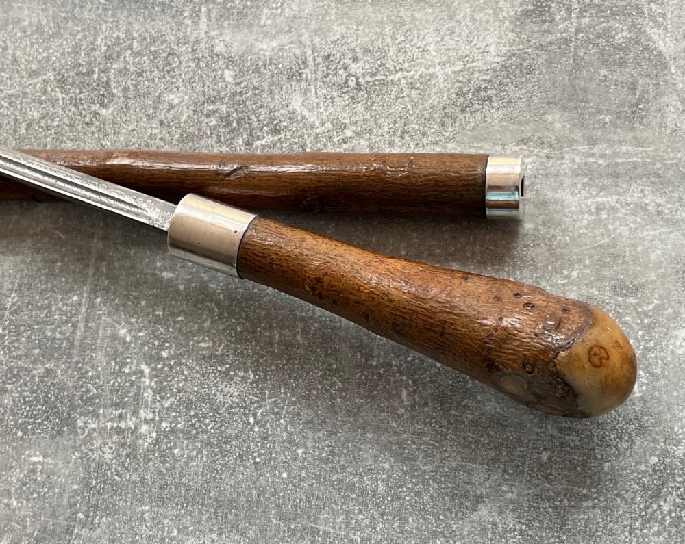 An antique chestnut wood sword stick shown unsheathed beside its shaft, featuring a root ball knob handle, silver collar mount, and long steel blade. View VIII