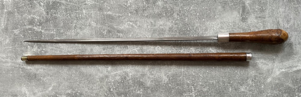 An antique chestnut wood sword stick shown unsheathed beside its shaft, featuring a root ball knob handle, silver collar mount, and long steel blade. View XIV