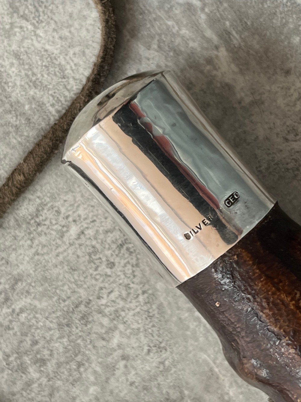 An antique sword stick with a dark brown leather-covered shaft, a silver knop top, and a partially drawn steel blade decorated with gold-toned etchings. View III