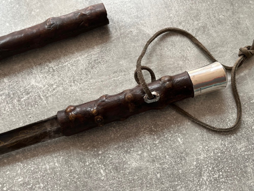 An antique sword stick with a dark brown leather-covered shaft, a silver knop top, and a partially drawn steel blade decorated with gold-toned etchings. View IV