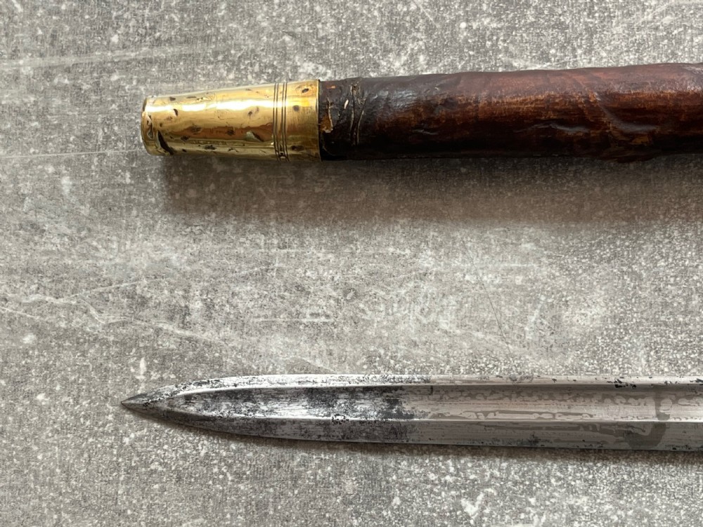 An antique sword stick with a dark brown leather-covered shaft, a silver knop top, and a partially drawn steel blade decorated with gold-toned etchings. View VIII