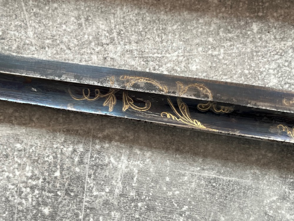 An antique sword stick with a dark brown leather-covered shaft, a silver knop top, and a partially drawn steel blade decorated with gold-toned etchings. View X