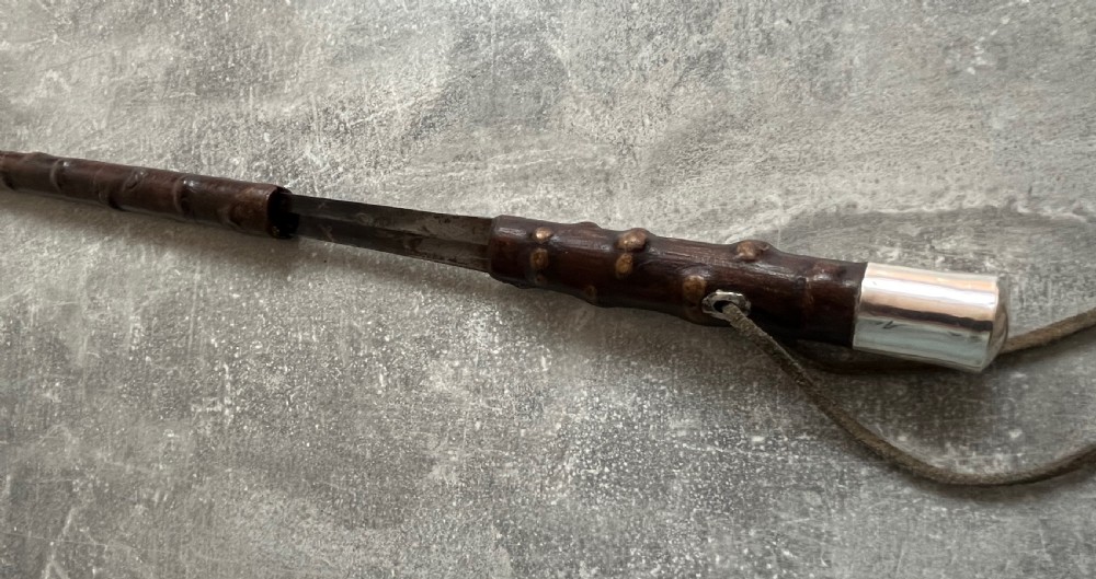 An antique sword stick with a dark brown leather-covered shaft, a silver knop top, and a partially drawn steel blade decorated with gold-toned etchings. View XIII