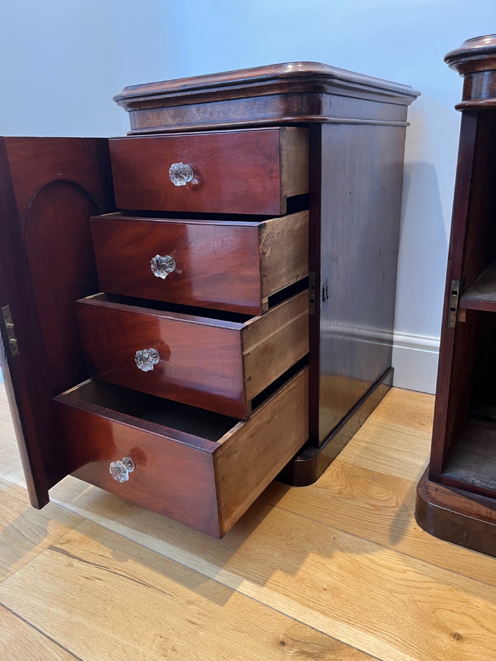 A matching pair of antique burr walnut bedside cabinets featuring single door cupboards with recessed arched panels and plinth bases. View VI