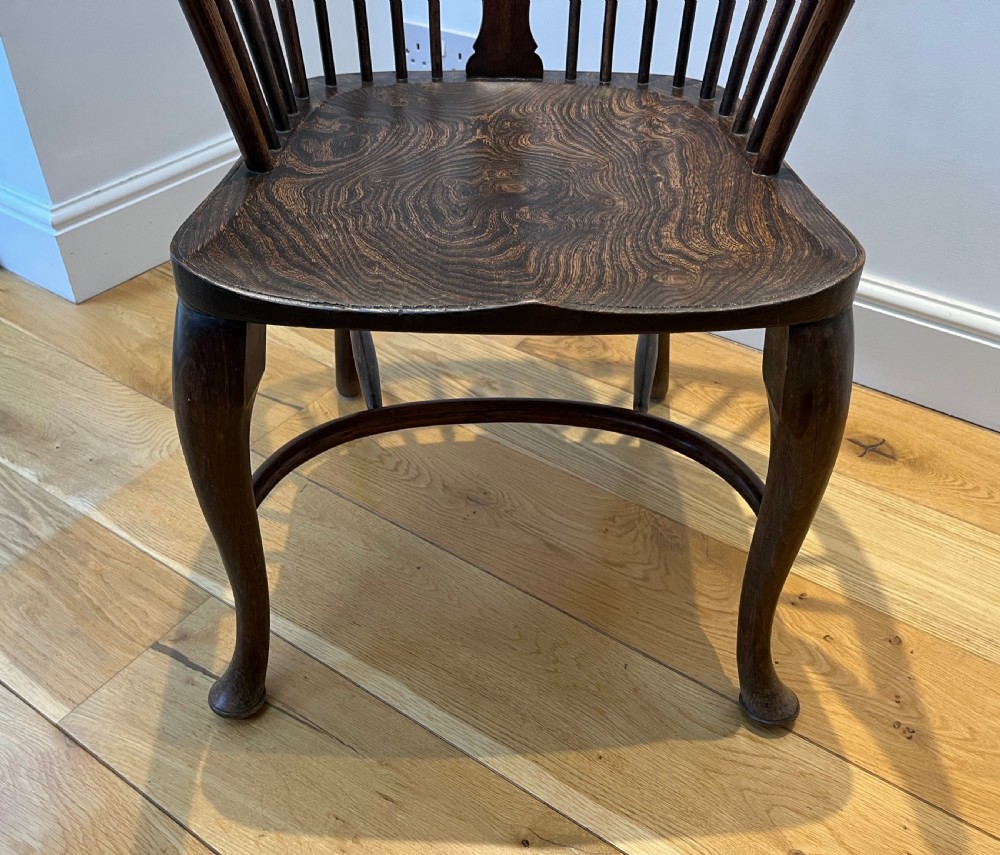 A dark brown wooden Windsor armchair featuring a high hoop back with a wheel-motif central splat, curved armrests, a contoured saddle seat, and front cabriole legs. View VIII