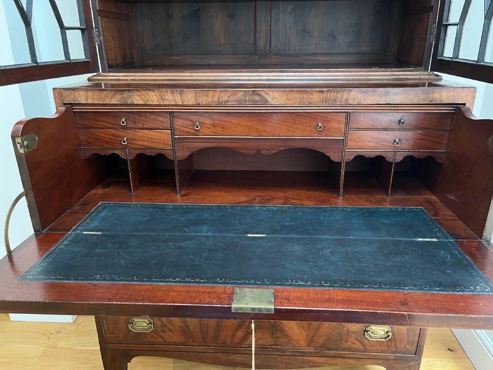 A Georgian mahogany secretaire bookcase featuring a double door upper cabinet with diamond astragal glazing, brass finials, and a lower chest of four drawers with brass drop handles. View IX