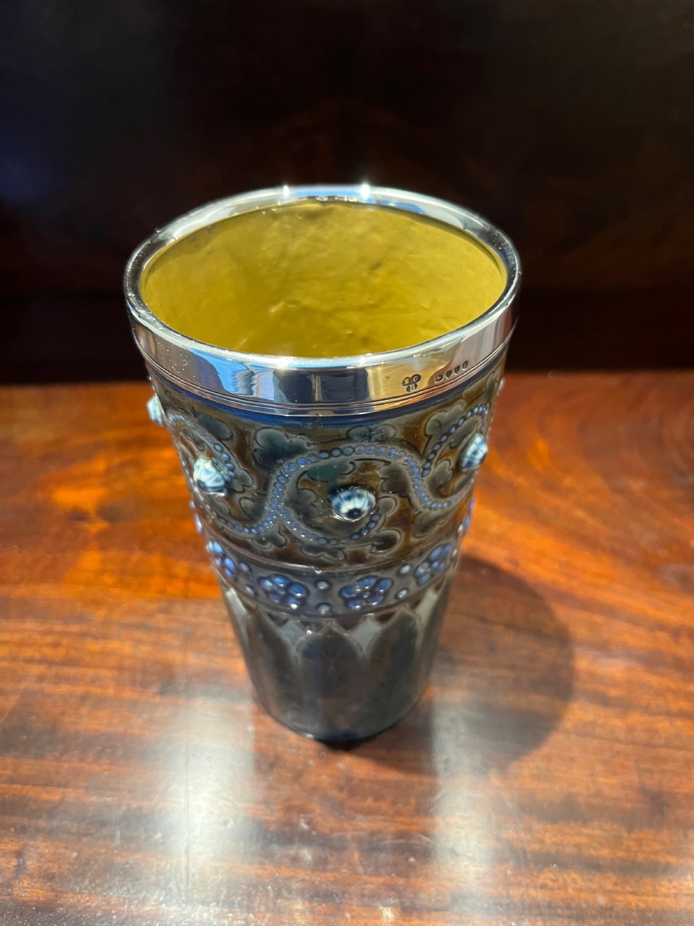 A Victorian Doulton Lambeth stoneware beaker featuring raised beaded scrollwork, floral motifs, and a hallmarked silver rim. View III