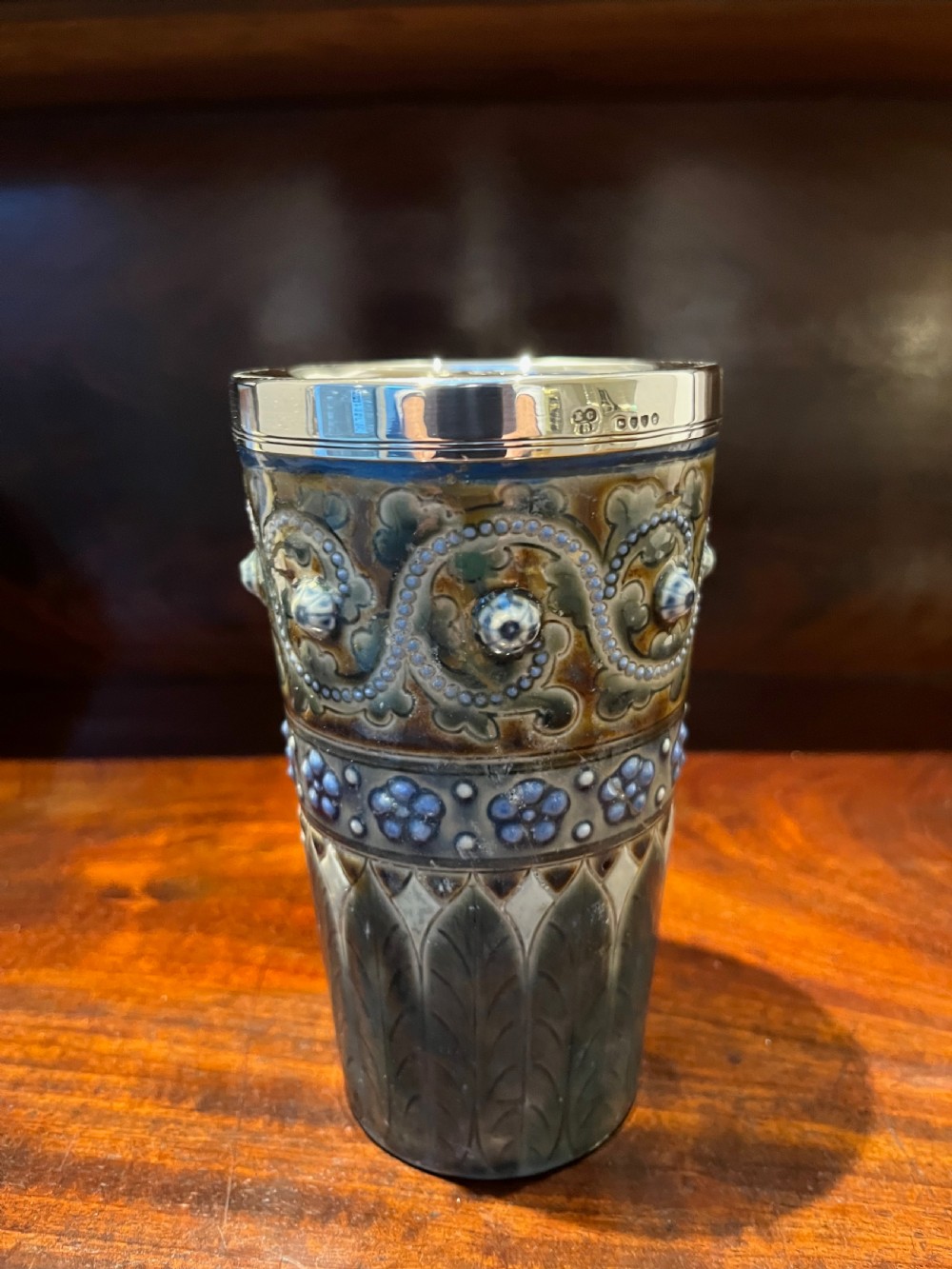 A Victorian Doulton Lambeth stoneware beaker featuring raised beaded scrollwork, floral motifs, and a hallmarked silver rim. View IV