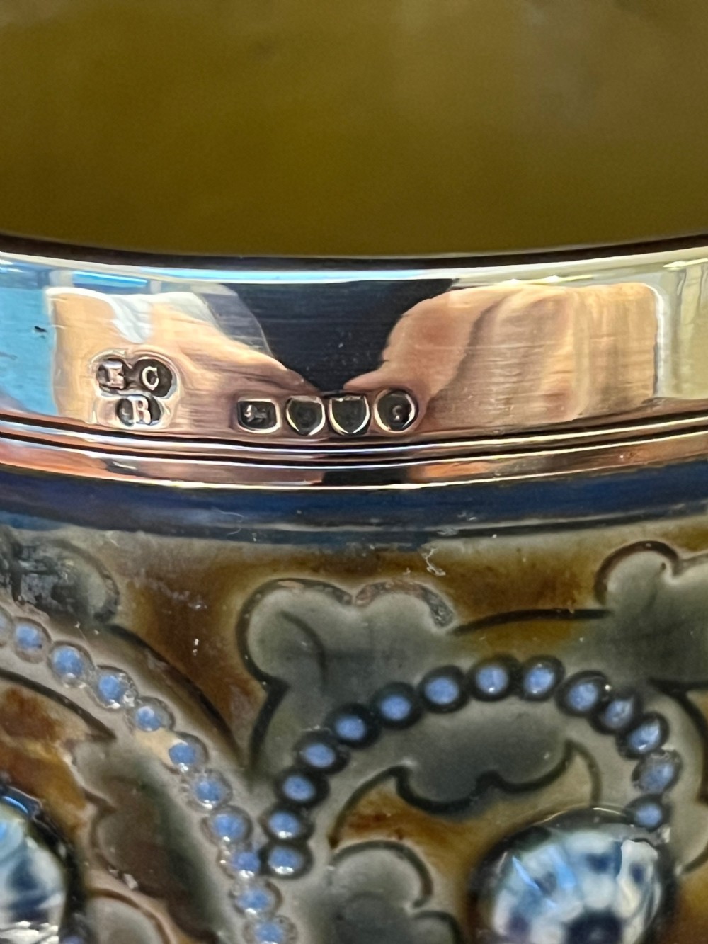 A Victorian Doulton Lambeth stoneware beaker featuring raised beaded scrollwork, floral motifs, and a hallmarked silver rim. View VIII