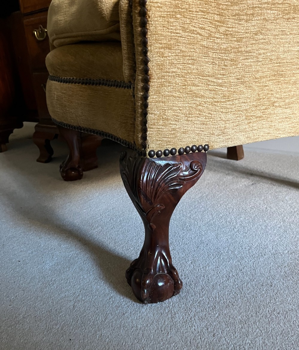 An Edwardian barrel back armchair upholstered in gold velvet with vertical fluted stitching, metal stud detailing, and carved dark wood legs. View II