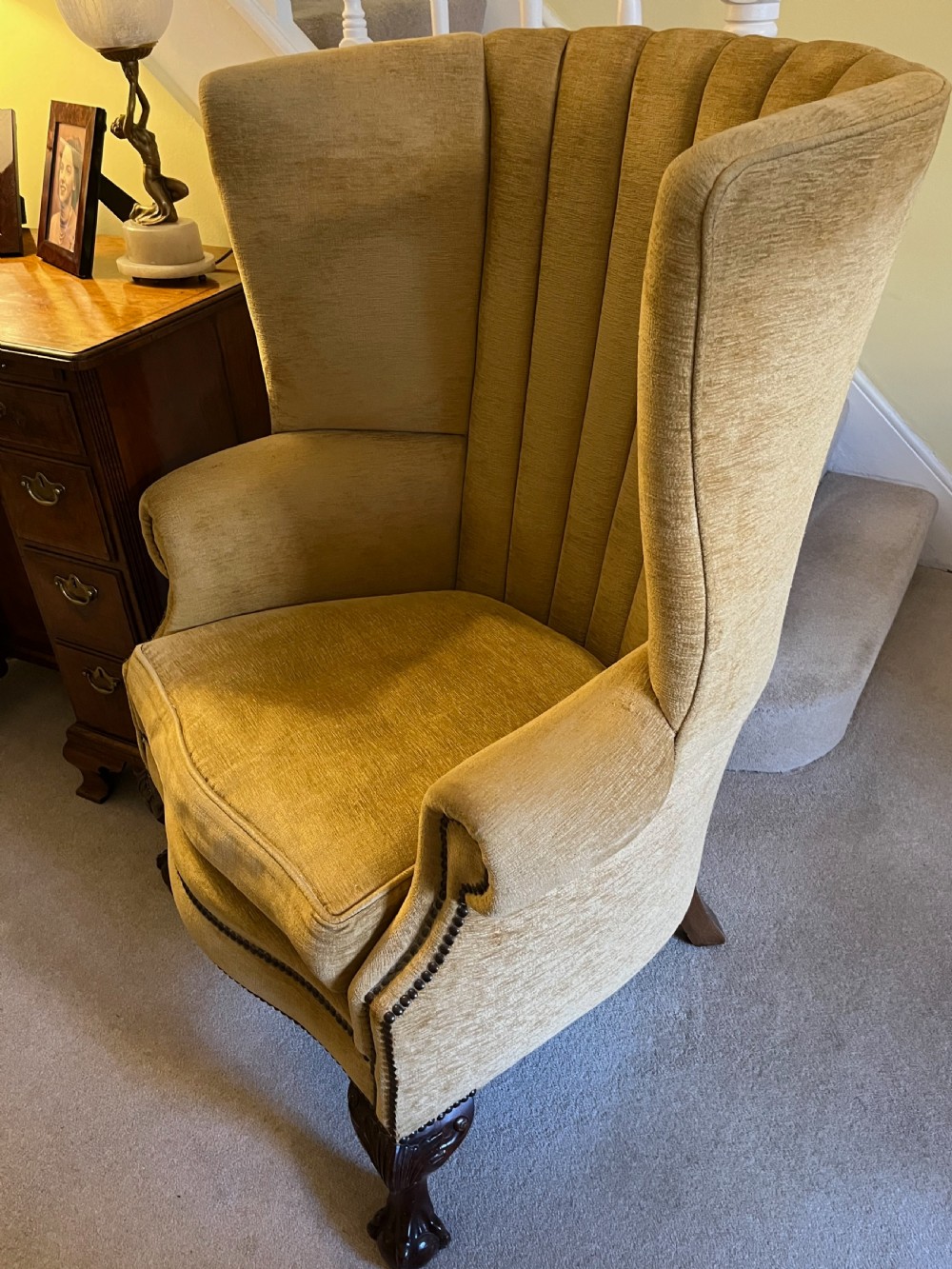 An Edwardian barrel back armchair upholstered in gold velvet with vertical fluted stitching, metal stud detailing, and carved dark wood legs. View V