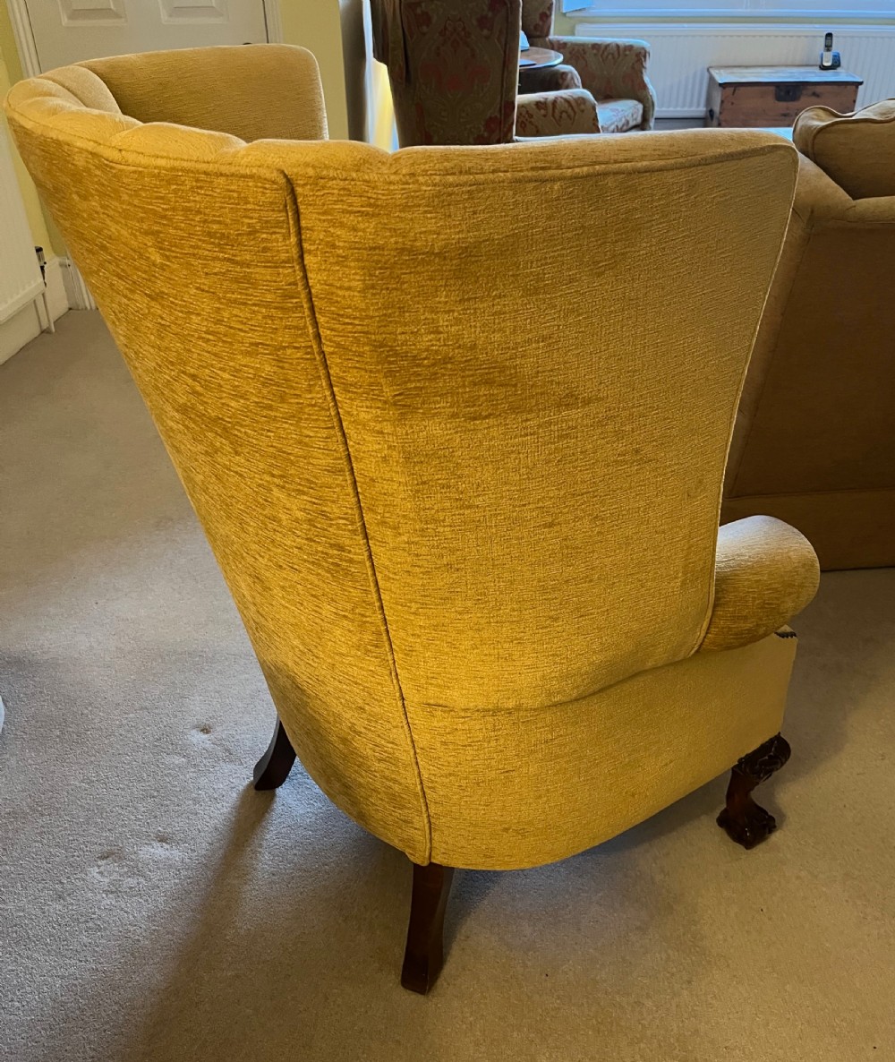 An Edwardian barrel back armchair upholstered in gold velvet with vertical fluted stitching, metal stud detailing, and carved dark wood legs. View VI