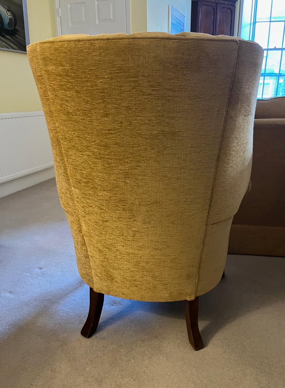 An Edwardian barrel back armchair upholstered in gold velvet with vertical fluted stitching, metal stud detailing, and carved dark wood legs. View VII