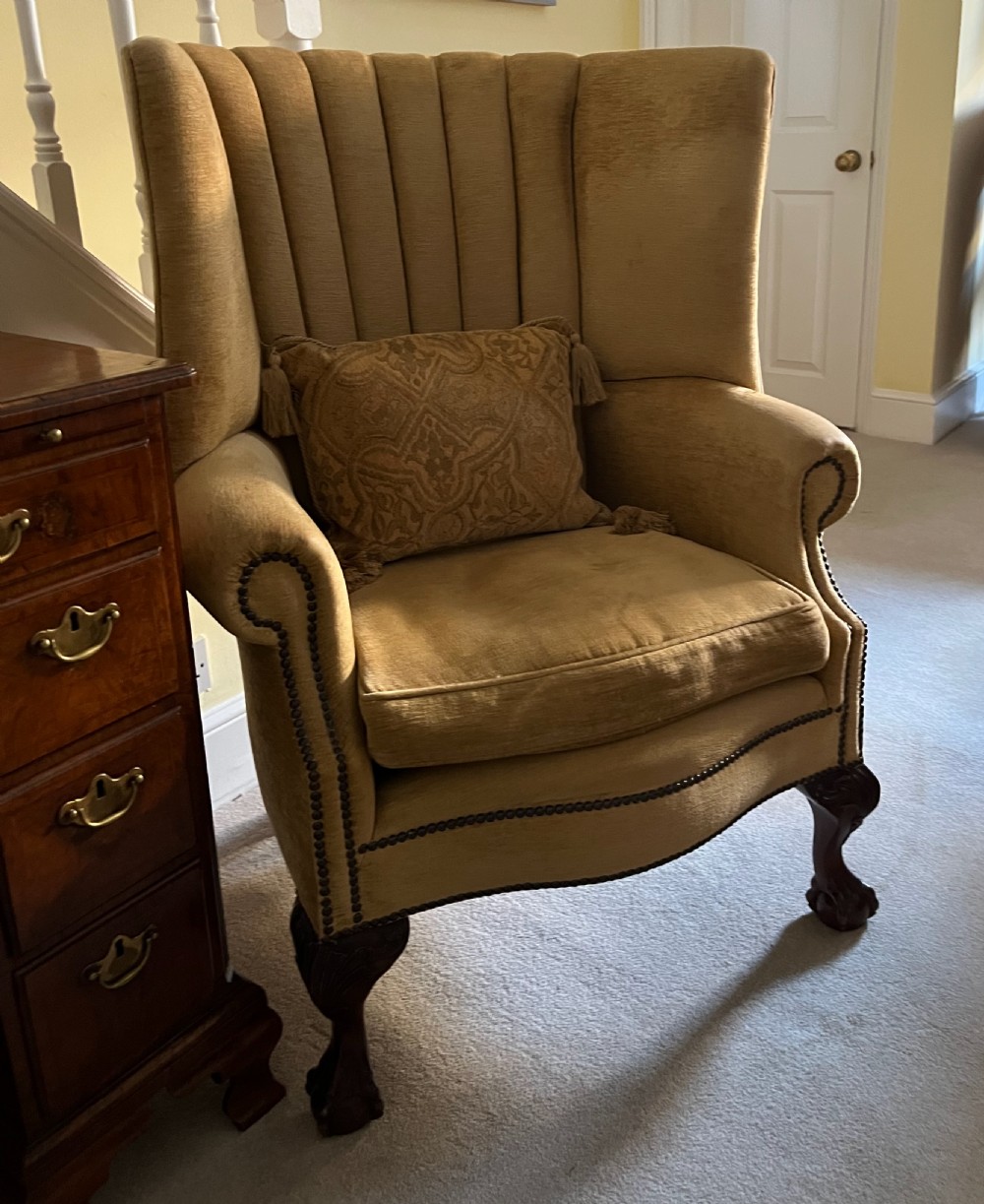 An Edwardian barrel back armchair upholstered in gold velvet with vertical fluted stitching, metal stud detailing, and carved dark wood legs. View IX