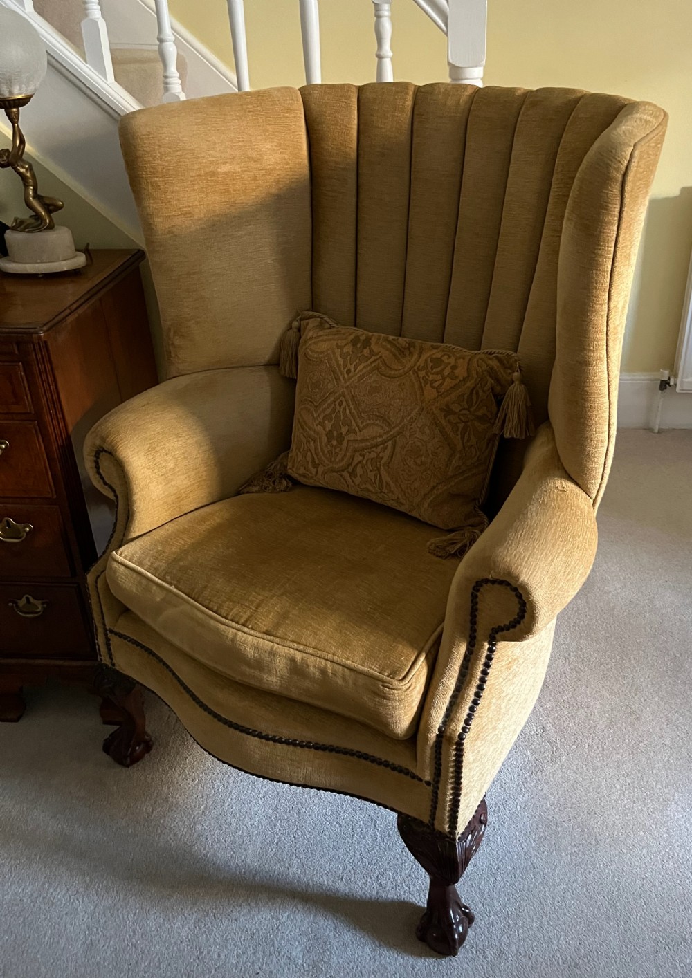 An Edwardian barrel back armchair upholstered in gold velvet with vertical fluted stitching, metal stud detailing, and carved dark wood legs. View X