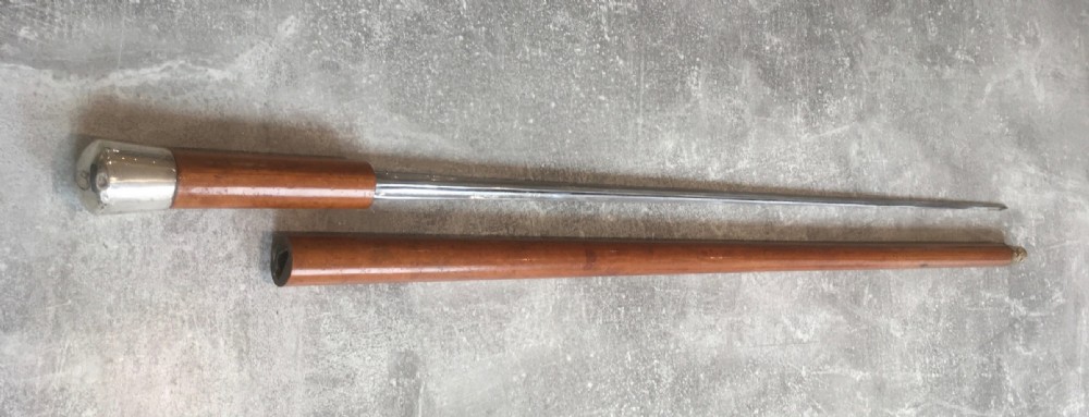 An antique Malacca cane walking stick featuring a smooth turned wood shaft, a brass ferrule at the tip, and a silver cap handle. View III