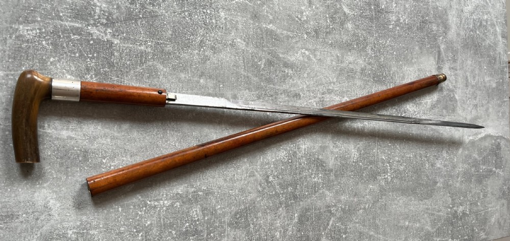 An antique Malacca wood walking stick unsheathed to reveal an etched steel Toledo blade alongside a silver collar and horn handle. View VI