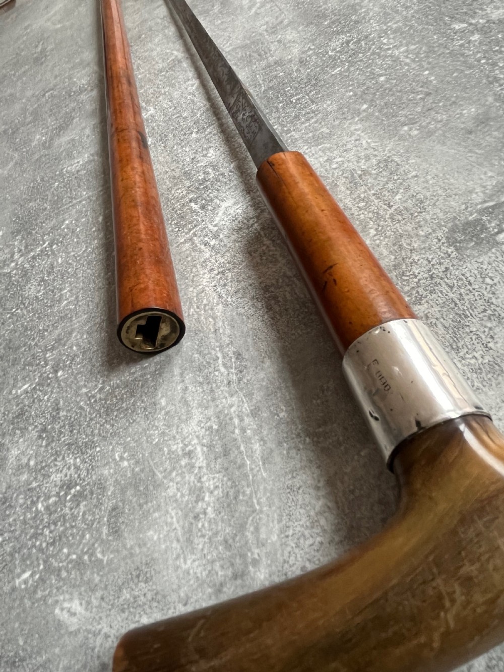 An antique Malacca wood walking stick unsheathed to reveal an etched steel Toledo blade alongside a silver collar and horn handle. View XI