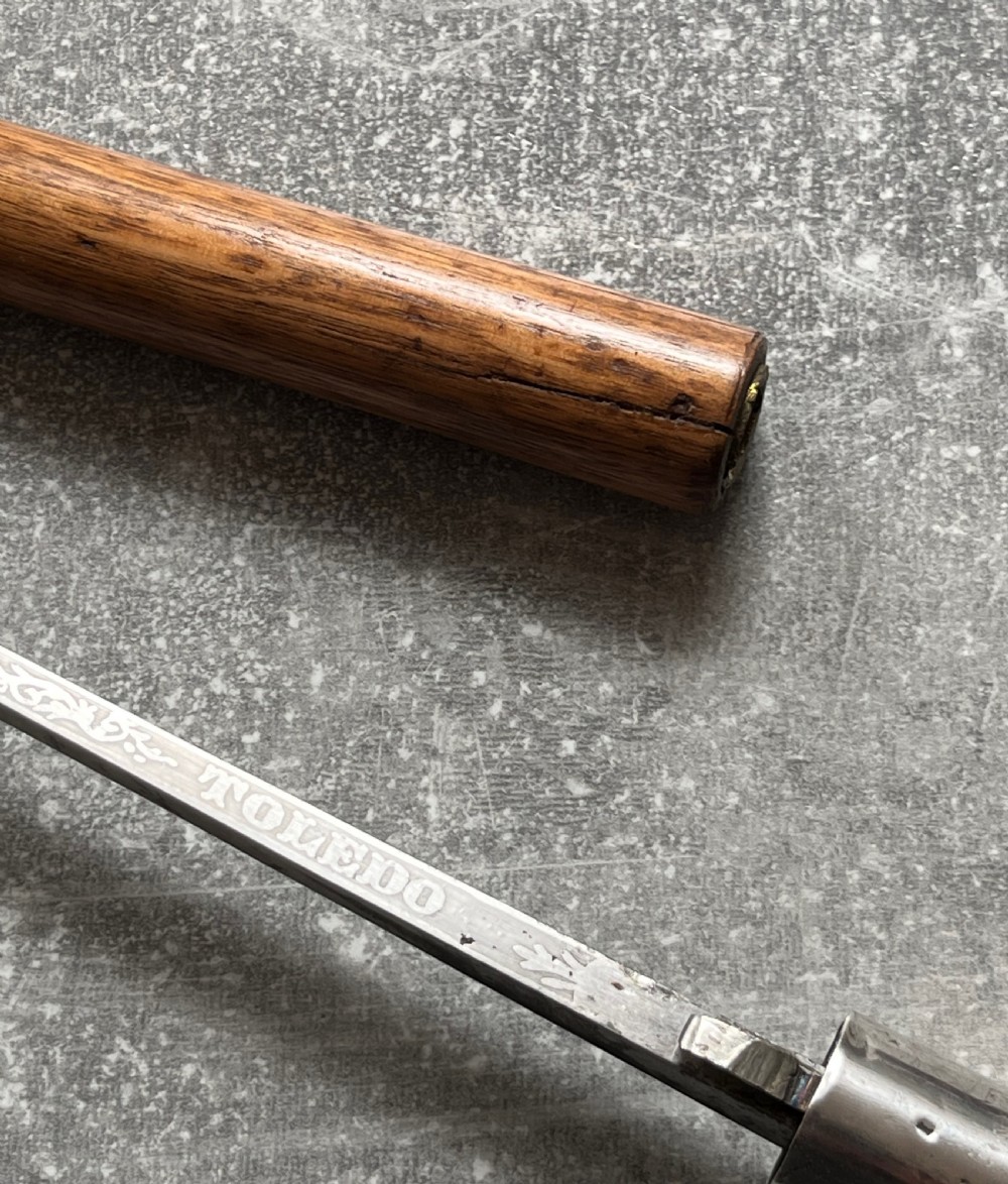 An antique crook-handled malacca walking cane unsheathed to reveal a long, slender steel sword blade beside its hollow wooden shaft. View VII