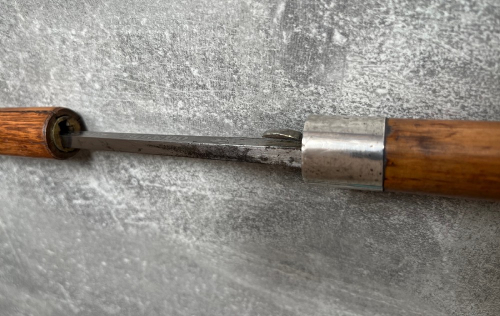 An antique crook-handled malacca walking cane unsheathed to reveal a long, slender steel sword blade beside its hollow wooden shaft. View XIII