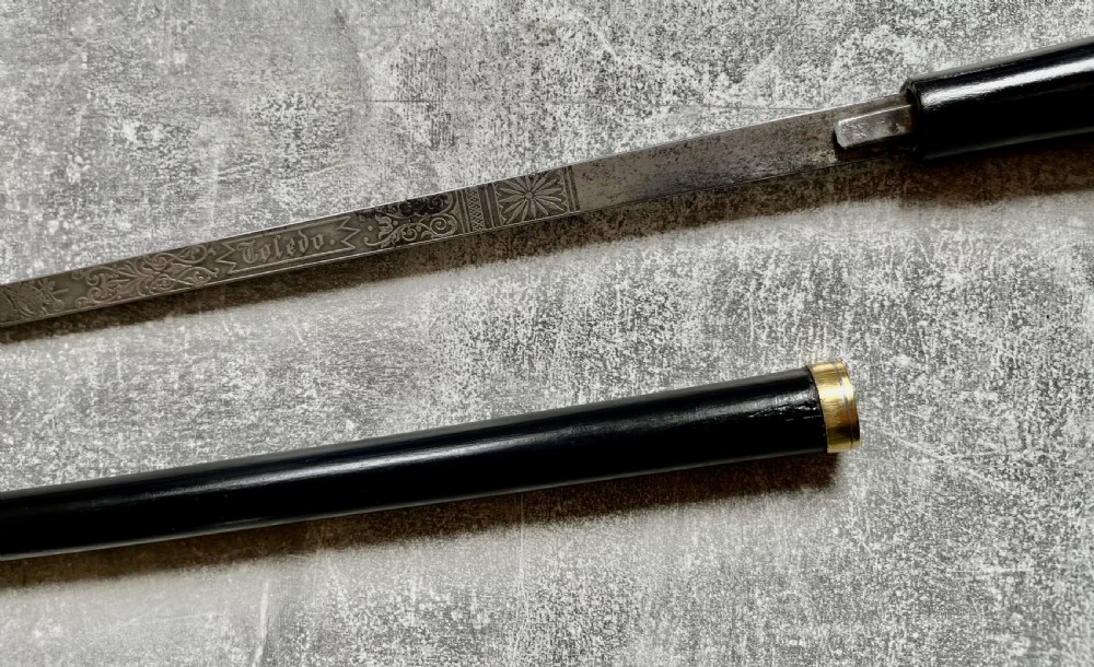 A Victorian ebonised wood walking stick shown in two parts alongside a slender concealed steel Toledo blade. View III