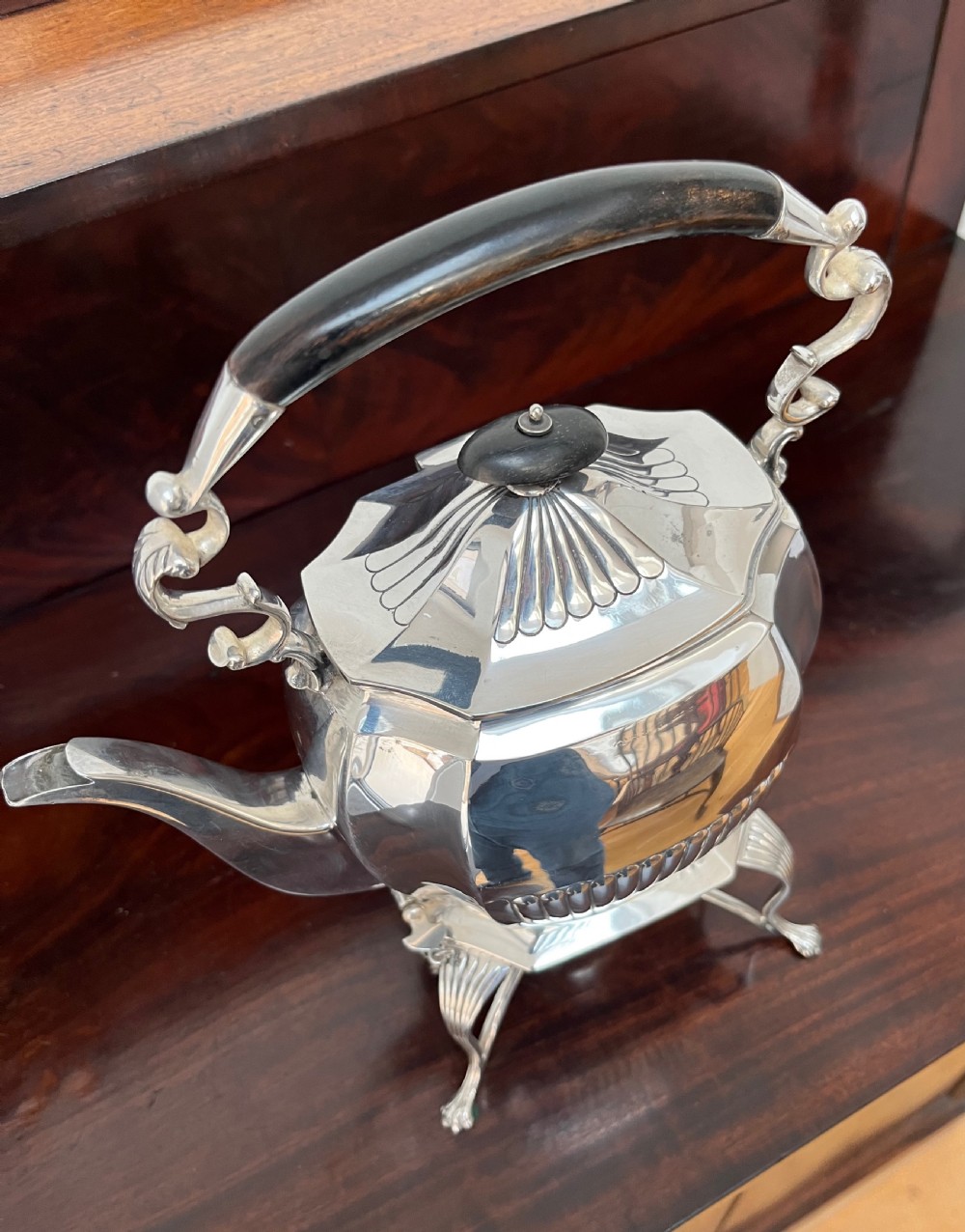 A silver-plated spirit kettle with a fluted lower body, dark wooden handle, gooseneck spout, and matching stand containing an alcohol burner below. View XIII
