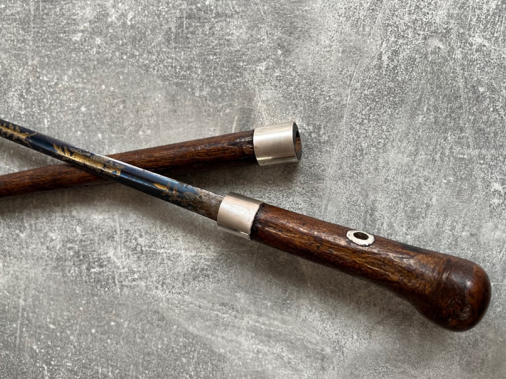 A late 19th-century dark hazel wood walking stick with a curved handle, silver collar, upper eyelet detail, and a metallic ferrule base. View III