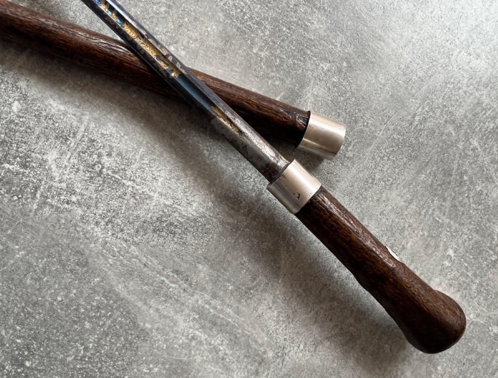 A late 19th-century dark hazel wood walking stick with a curved handle, silver collar, upper eyelet detail, and a metallic ferrule base. View IV