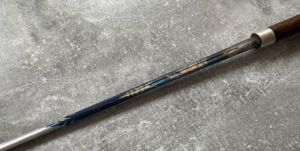 A late 19th-century dark hazel wood walking stick with a curved handle, silver collar, upper eyelet detail, and a metallic ferrule base. View VI