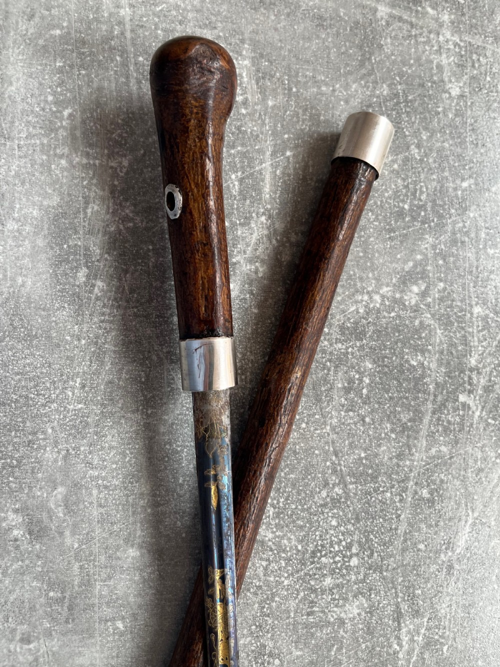 A late 19th-century dark hazel wood walking stick with a curved handle, silver collar, upper eyelet detail, and a metallic ferrule base. View XI