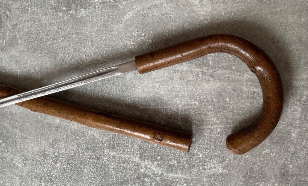 An antique hazel wood crook-handled walking stick shown unsheathed beside its concealed etched steel blade. View III