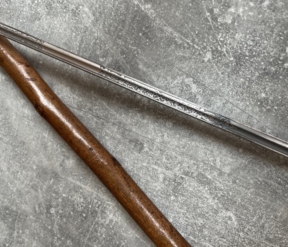 An antique hazel wood crook-handled walking stick shown unsheathed beside its concealed etched steel blade. View V