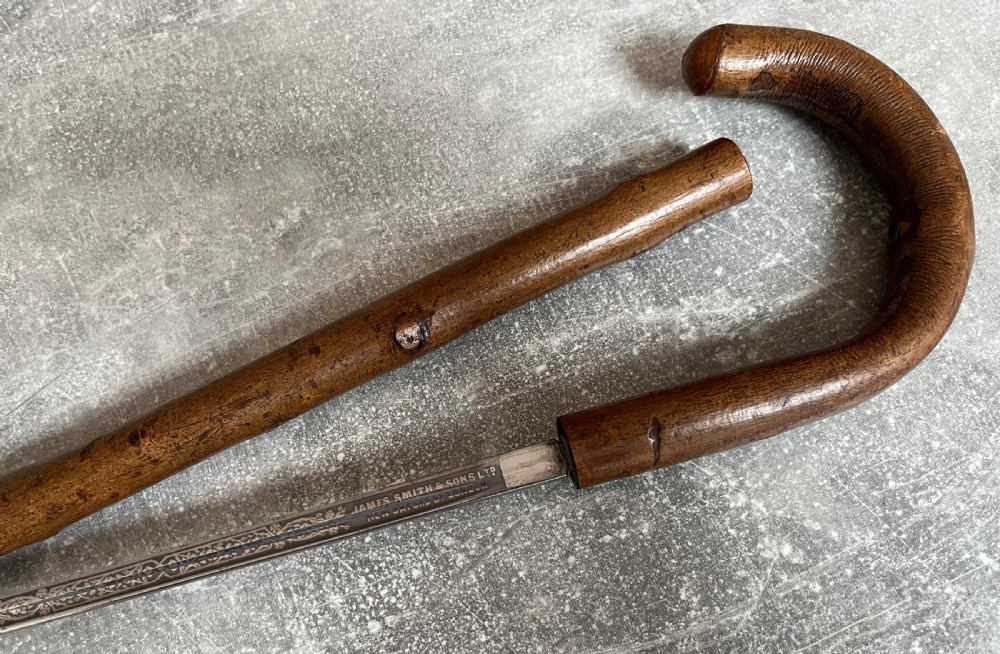 An antique hazel wood crook-handled walking stick shown unsheathed beside its concealed etched steel blade. View VII