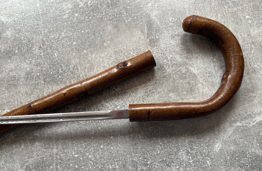 An antique hazel wood crook-handled walking stick shown unsheathed beside its concealed etched steel blade. View VIII
