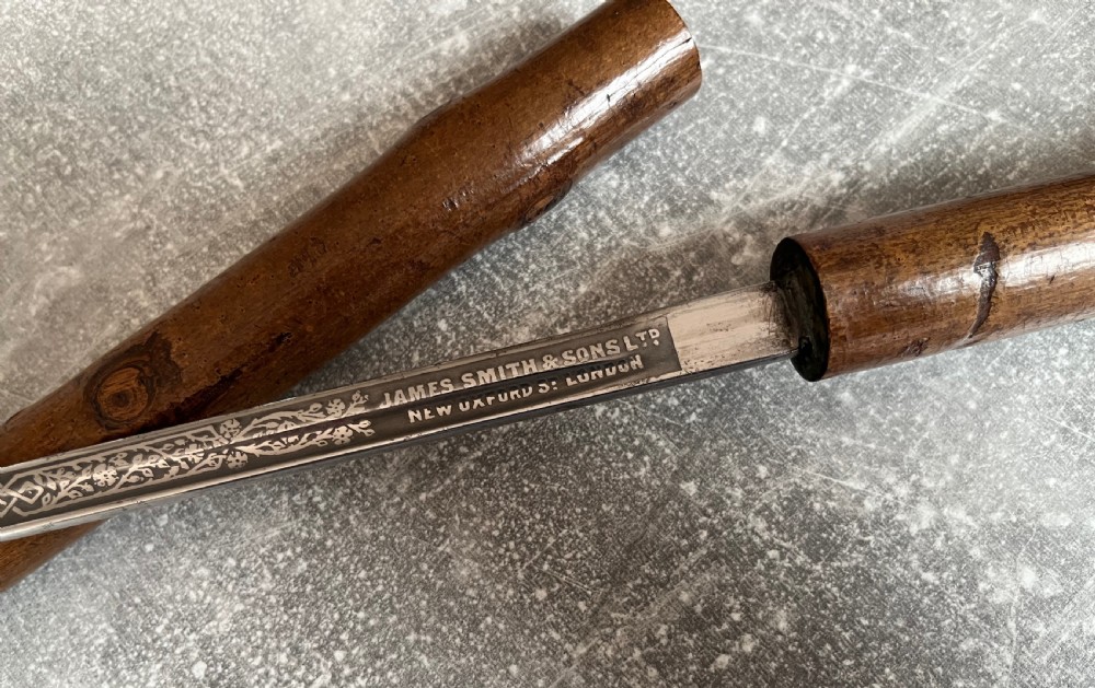 An antique hazel wood crook-handled walking stick shown unsheathed beside its concealed etched steel blade. View IX