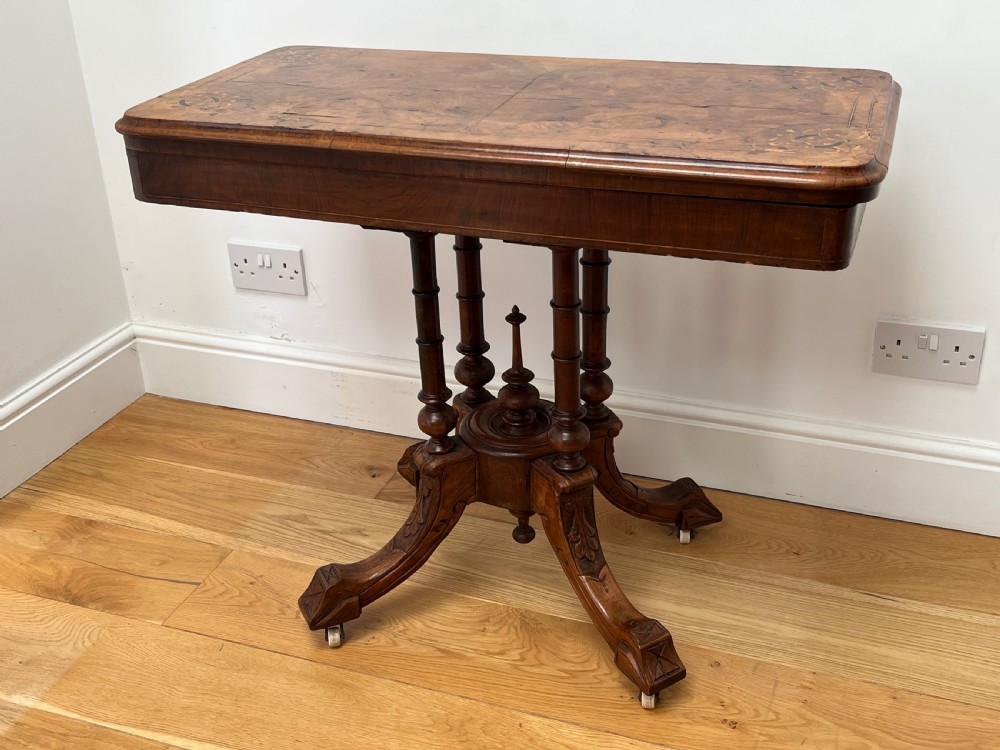 A Victorian burr walnut card table with an unfolded green baize surface resting on a carved pedestal base. View III