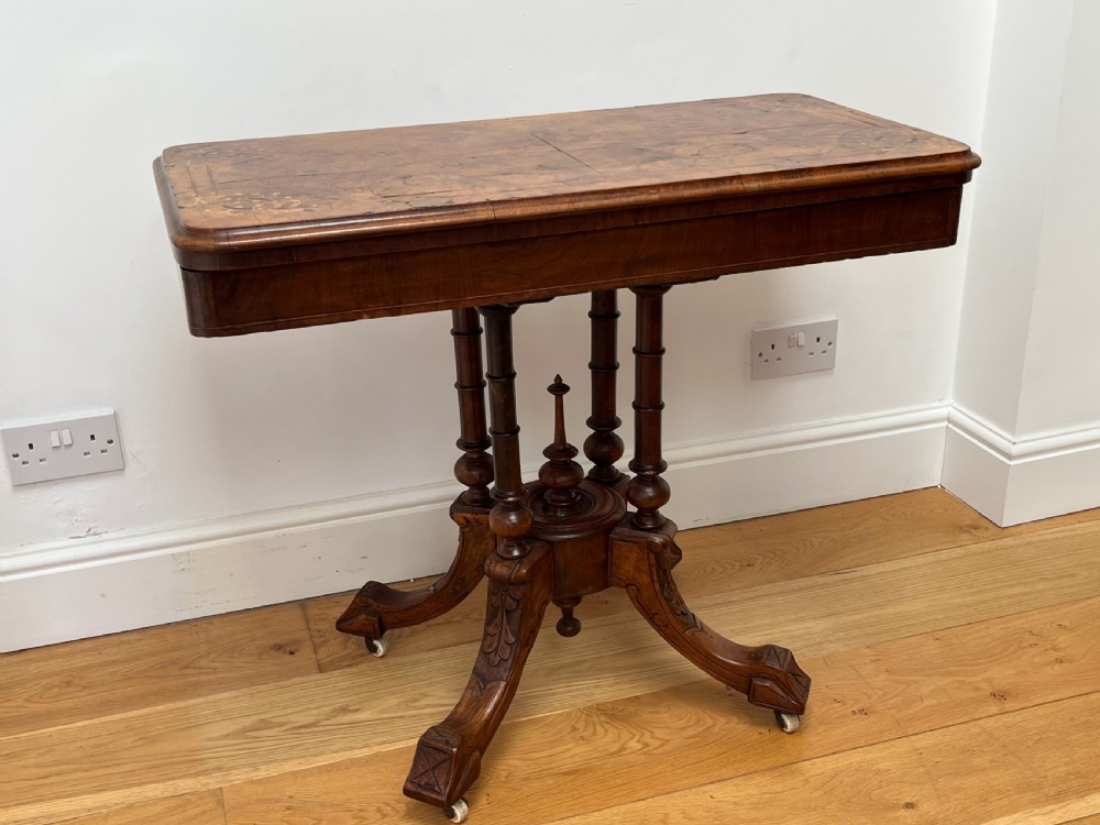 A Victorian burr walnut card table with an unfolded green baize surface resting on a carved pedestal base. View IV