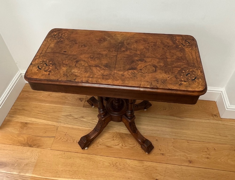 A Victorian burr walnut card table with an unfolded green baize surface resting on a carved pedestal base. View V