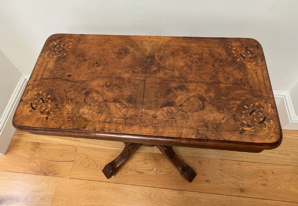 A Victorian burr walnut card table with an unfolded green baize surface resting on a carved pedestal base. View VI