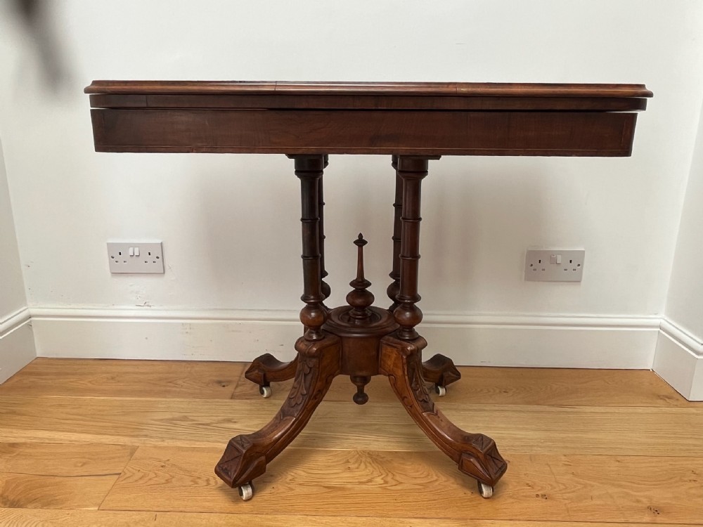 A Victorian burr walnut card table with an unfolded green baize surface resting on a carved pedestal base. View VIII