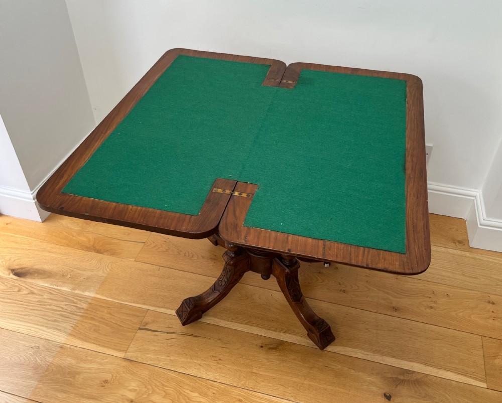 A Victorian burr walnut card table with an unfolded green baize surface resting on a carved pedestal base. View X