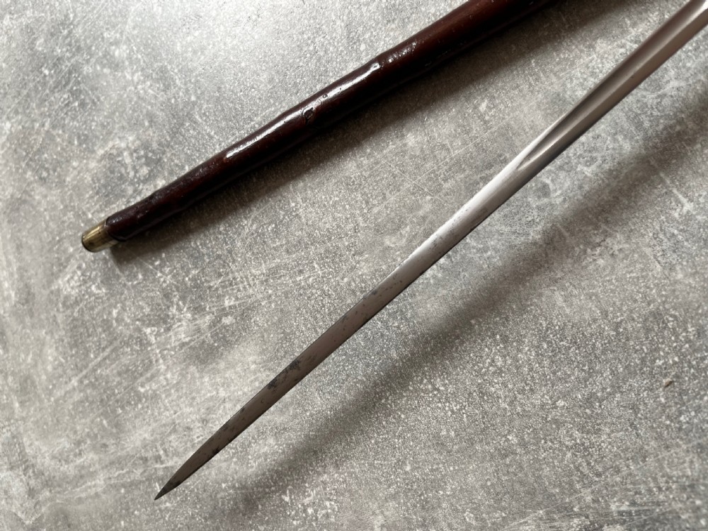 An antique cherrywood sword stick featuring a curved crook handle, a dark polished wood shaft, and a drawn steel blade with etched markings. View XIII