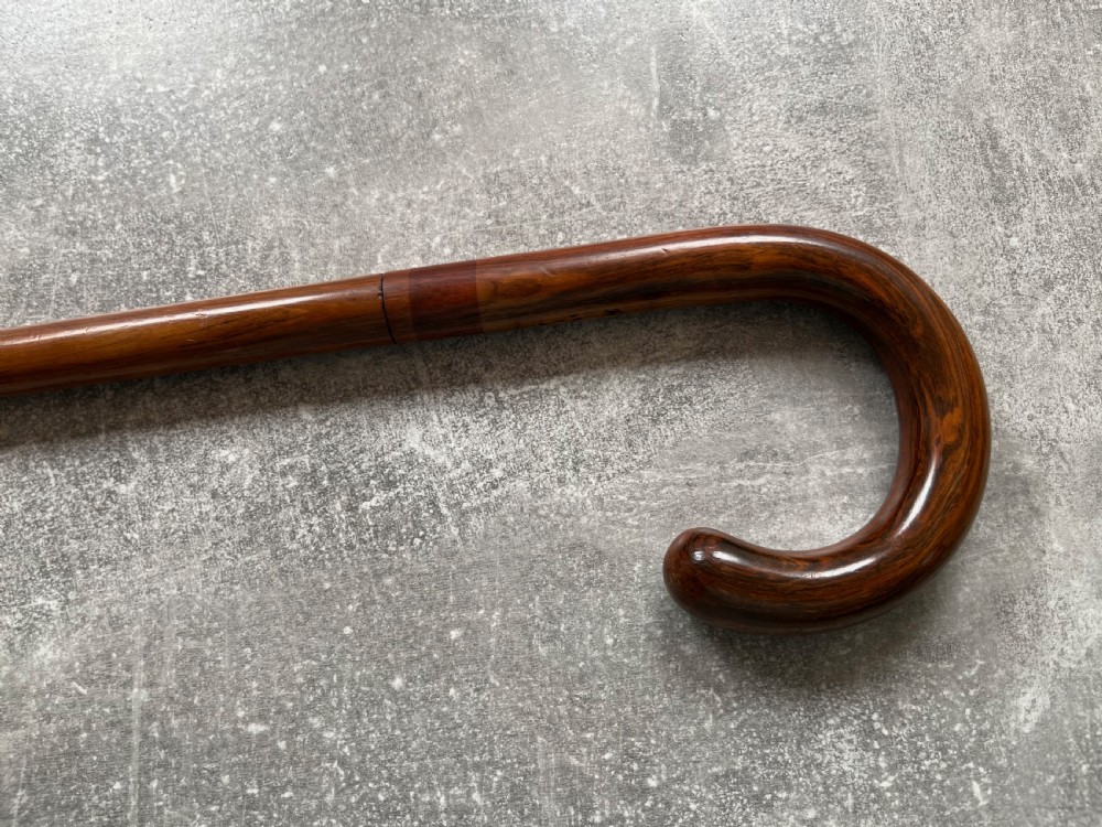 An antique brown Malacca wood walking stick with a curved crook handle, shown unsheathed to reveal an etched steel Toledo blade alongside its wooden sheath. View XI
