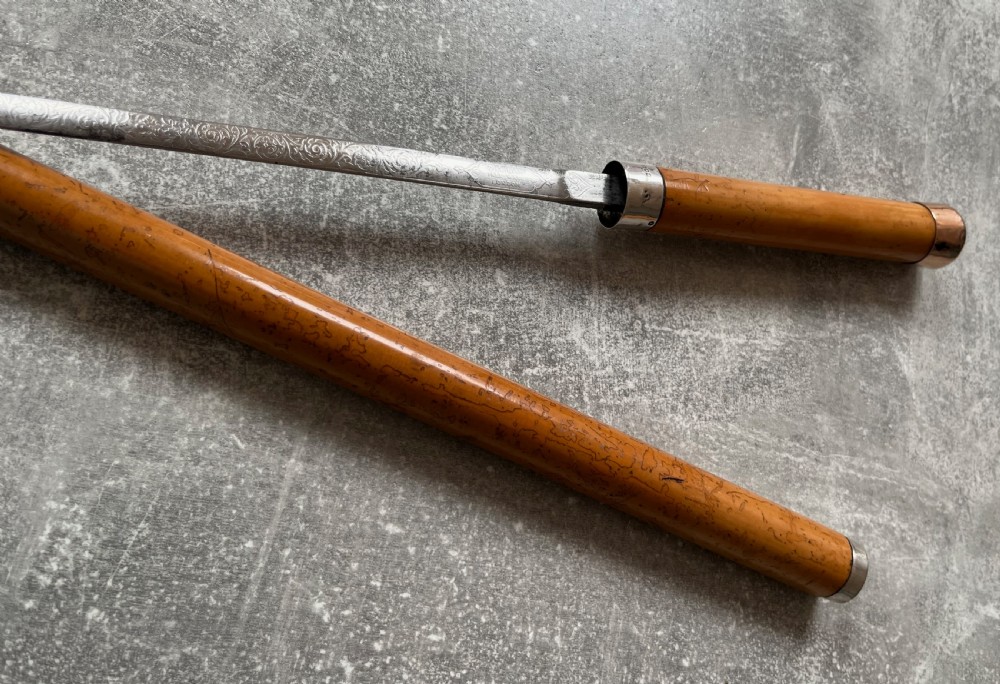 An antique malacca walking cane separated to reveal a tapered steel sword blade with silver and gold mounts. View IX