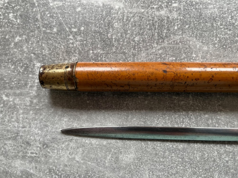 An antique malacca walking cane separated to reveal a tapered steel sword blade with silver and gold mounts. View X