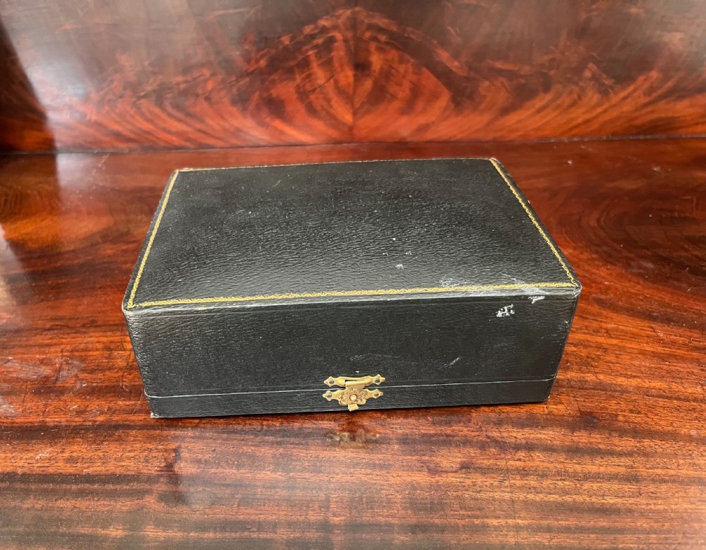 A cased set of six silver napkin rings with embossed relief scenes inside a black silk and velvet box. View X