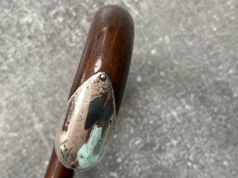 A dark brown polished hardwood walking stick featuring a curved crook handle with silver mounts and a metal ferrule at the tip. View IV