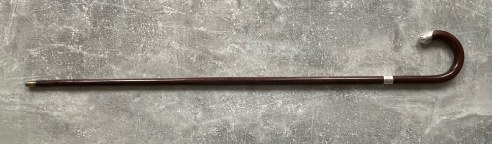 A dark brown polished hardwood walking stick featuring a curved crook handle with silver mounts and a metal ferrule at the tip. View VII