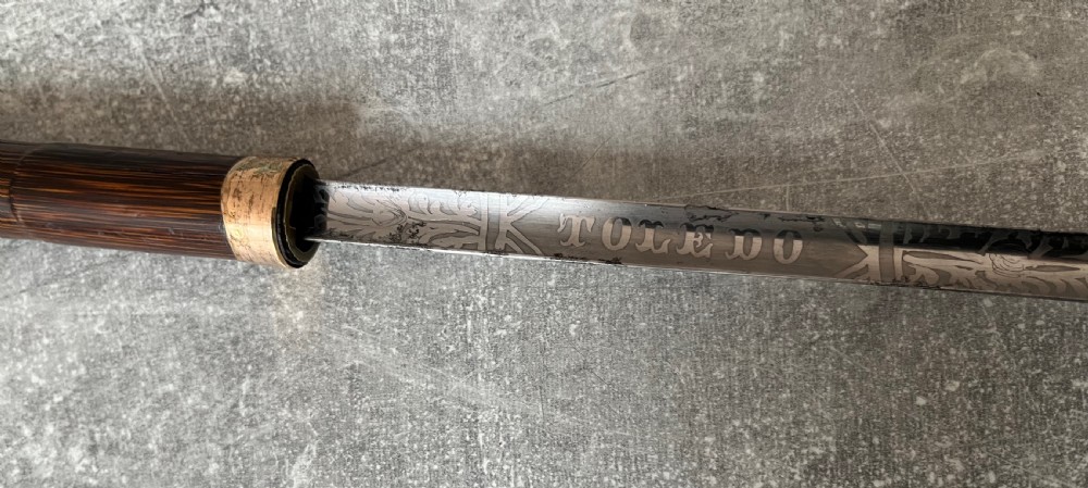 A dark wood walking stick featuring a crook handle and faux bamboo carved nodes, unsheathed to reveal a long steel blade alongside its wooden casing. View IV